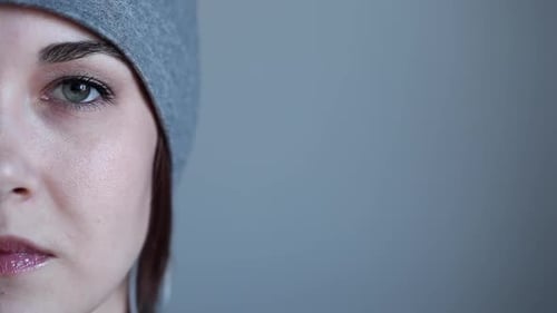 Woman in Beanie Opens Eyes and Smiles, Close Up
