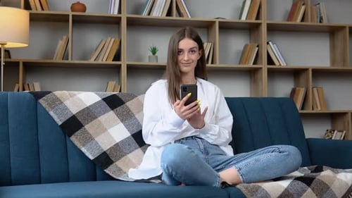 Young Woman Relaxing With Mobile Phone on Sofa