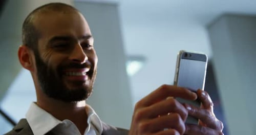 Smiling Businessman Using Phone in Modern Office