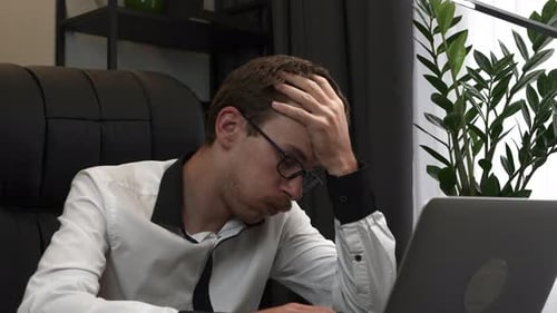 Stressed Man Working On Laptop In Office