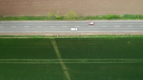 Aerial View of Moving Cars on a Fast Road Between Green and Ground Field