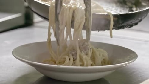Serving Creamy Pasta Dish with Tongs