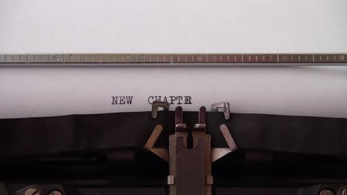 Typing phrase NEW CHAPTER on retro typewriter. Close up.