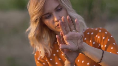 Attractive Young Woman Hands with Golden Glitters in the Field on Sunset