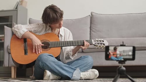 Young Adult Plays Guitar, Records with Phone
