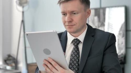 Man Smiling, Using Tablet in Modern Office