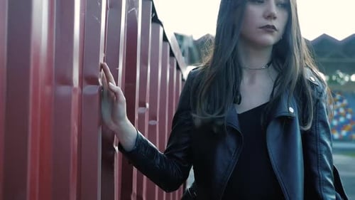 Young Woman Walks Next to Red Wall