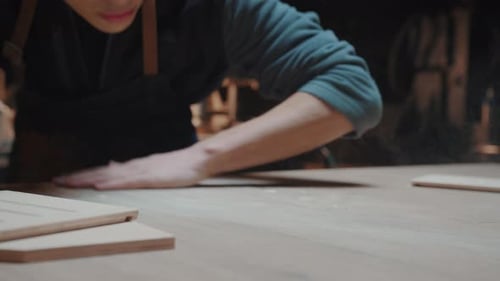 Young Man Cleaning Up Sawdust in Woodworking Shop