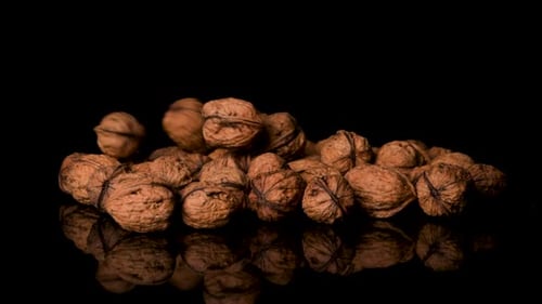 Heap of Walnuts on Reflective Black Background