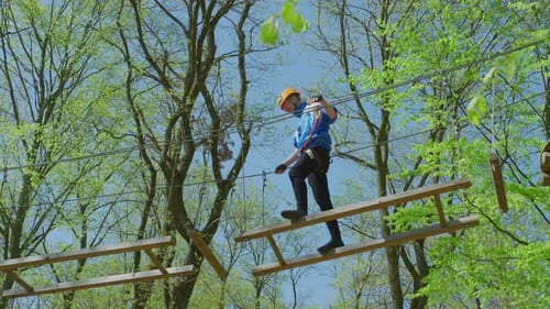 Person on Ropes Course Ladder in Green Forest
