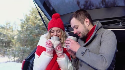 Couple Enjoying Hot Drinks in Snowy Winter Landscape