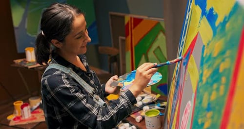 A Talented Girl Stands Next to a Canvas on Which She is Creating a Modern