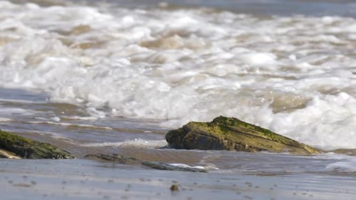 Ocean wave rolling and crashing on beach rock closeup (SLOW MOTION)