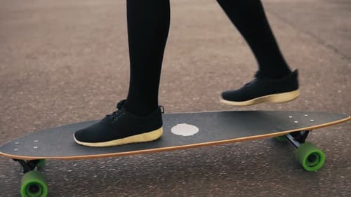 Closeup View of Woman's Legs in Black Sneakers Skateboarding on the Road in the City