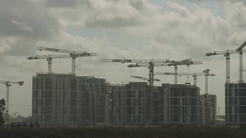 Timelapse of a large construction site with many cranes working over buildings