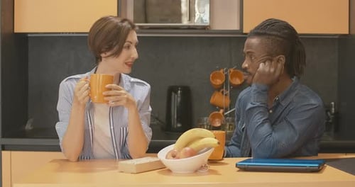 Young Adults Talk at Kitchen Table with Coffee