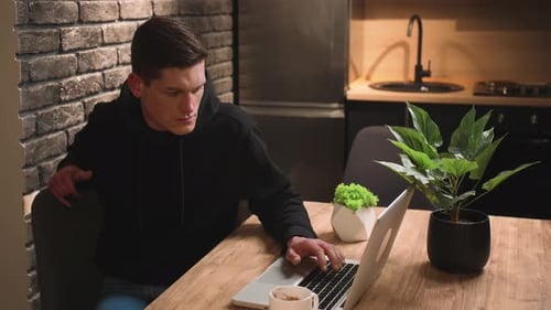 Young Adult Using Laptop at Wooden Table