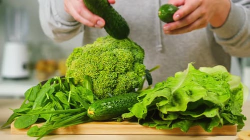 Person Arranging Fresh Green Vegetables on Cutting Board