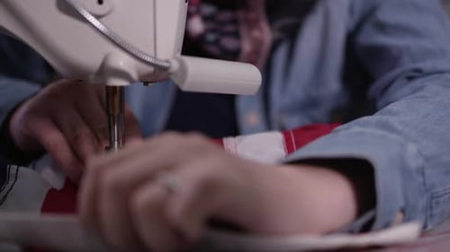 Up close view of hands feeding flag throug sewing machine