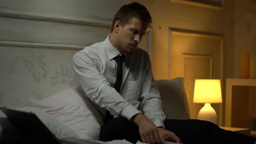 Man Working Late in Bed with Laptop and Papers