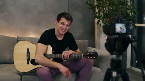 Smiling Young Man Playing Guitar and Vlogging