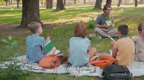 Creative Primary School Teacher Teaching Kids about Plants in Park