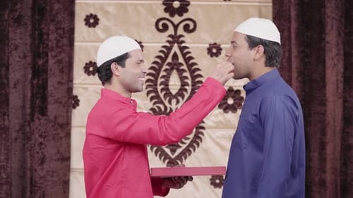 Muslim man giving sweets to his friend on Eid