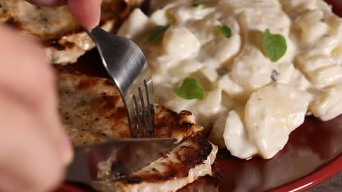 Cutting Grilled Pork Chop with Potato Salad