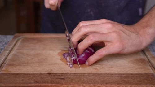 Man Skillfully Chopping Red Onion on Cutting Board