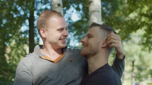 Men Smile and Kiss in a Beautiful Park