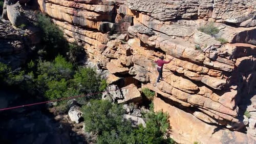 Male highliner walkng on a rope over rocky mountains 4k