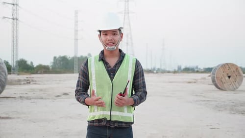Construction Worker with Walkie-Talkie near Power Lines