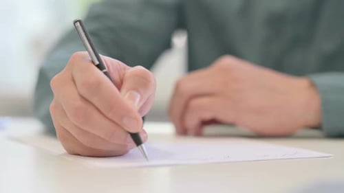 Gros plan des mains d'un homme d'âge moyen écrivant sur papier