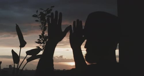 Silhouette eines meditierenden Mannes mit Sonnenuntergang und Pflanzen im Hintergrund