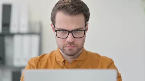 Close Up of Young Man with Laptop Looking at the Camera
