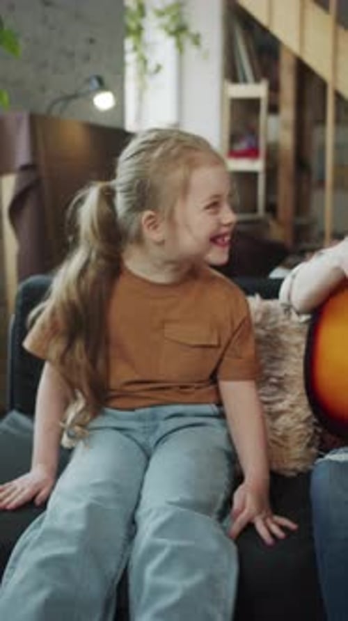 Cheerful Woman Singing Guitar with Happy Child at Home