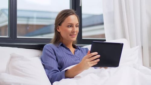 Woman Relaxes in Bed with Tablet in Bedroom
