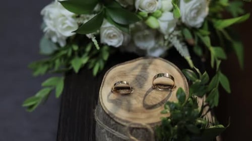 Beautiful Wedding Rings Lie on Wooden Stand with Wedding Bride's Bouquet