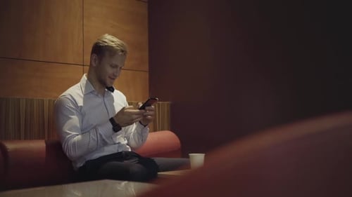Man Using Mobile Phone in Modern Office Lounge