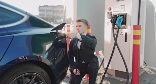 Man Charging Electric Car at Urban Station