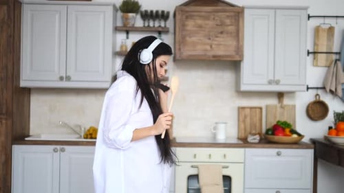 Woman Dancing and Singing in Kitchen with Headphones