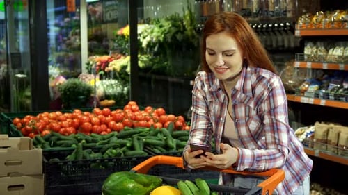 Woman Using Phone While Grocery Shopping