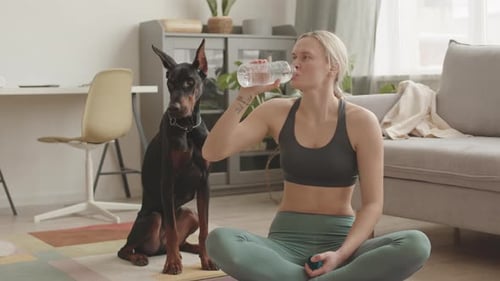 Woman Hydrating After Workout with Doberman Dog