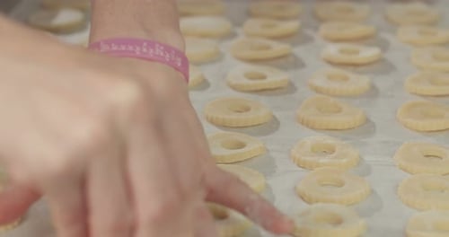 Bäcker bereitet Butterkekse mit Erdbeer-Marmelade und Puderzucker