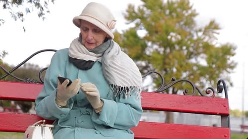 Senior Woman Using Smartphone on Park Bench