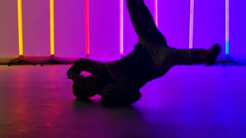 Un danseur expérimenté exécute des éléments complexes de break dance, tourne sur le sol et fait un stand sur la tête