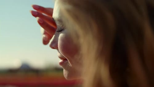 Gros plan Jolie femme regardant la lumière du soleil dans un parc avec des fleurs colorées