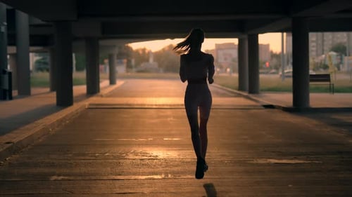 A Young Woman Runner is Training in the Summer Within a City