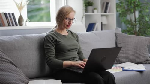 Woman Using Laptop On Couch At Home