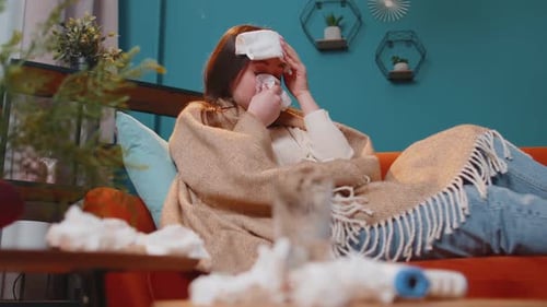 Portrait d'une jeune femme souffrant d'un rhume ou d'une allergie à carreaux couchée sur un canapé dans le salon à la maison